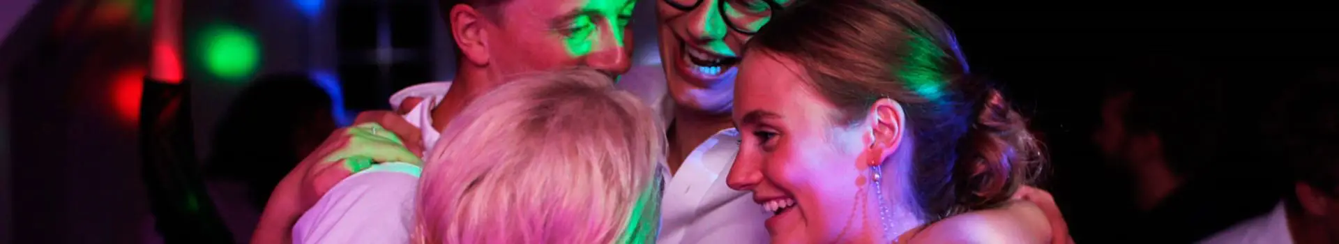 Bryllupsgjester samlet tett i en klem på dansegulvet i varmt lys
