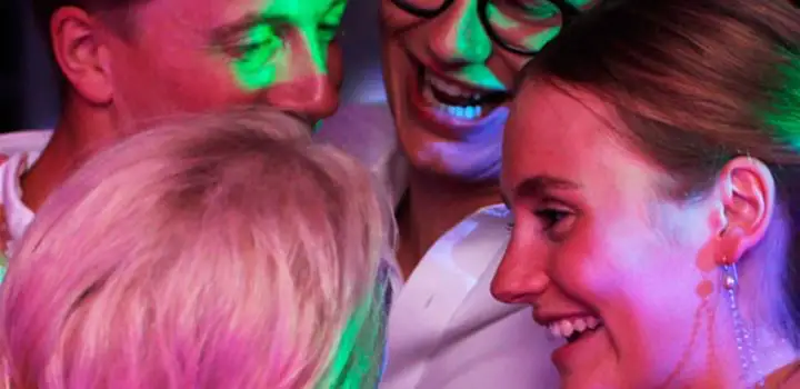 Bryllupsgjester samlet tett i en klem på dansegulvet i varmt lys