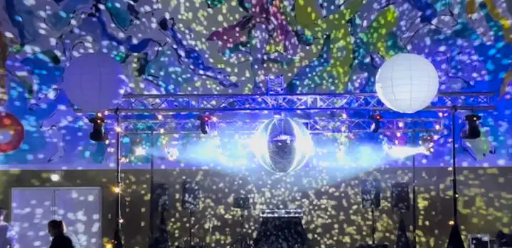 Festlokale med lysrigg i travers, discokule og prosjektorlys over dansegulvet