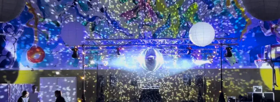 Festlokale med lysrigg i travers, discokule og prosjektorlys over dansegulvet
